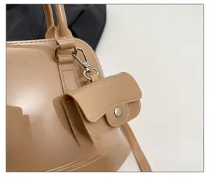 Detail of a beige jelly crossbody bag featuring a glossy mini pouch charm with silver clasp