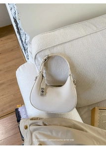 Detail of minimalist cream crescent bag with lychee grain leather and silver buckle