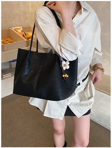 Sac fourre-tout en cuir noir porté par un modèle avec détail de charm marguerite blanche