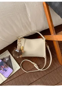 Close-up of cream textured leather handbag with plush charm and gold hardware detail