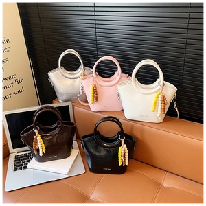 Detailed close-up of mini bucket bags in five colors on a leather sofa with bead charms