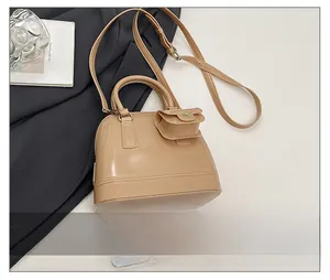 Detail showing beige jelly shell bag with mini pouch on a grey suit jacket background
