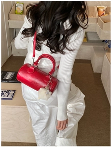 Dettaglio borsa baguette in pelle rosso vivo con ciondolo a forma di peluche