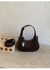 Detail of dark brown crescent bag showing pebble leather texture and silver zipper