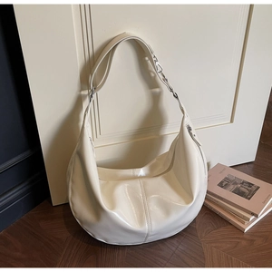 Detail of creamy white crescent bag featuring glossy leather and chain strap stitching