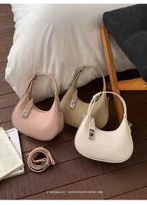 Detailed view of three lychee grain hobo bags with metal buckles on a wooden floor