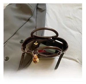 Macro view of spacious interior of dark brown patent leather bucket bag with daily items