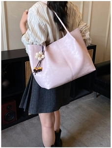 Vue latérale d'un grand sac cabas rose clair en cuir brillant avec charm floral