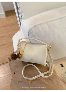 Detail of white lychee leather texture with gold hardware and plush monster charm