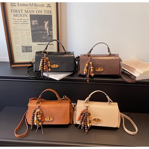 Detail view of four vintage crossbody bags in varied colors with tassel charms