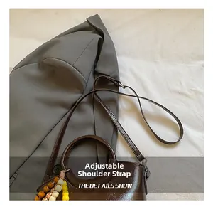 Detail of dark brown glossy bucket bag with bead pendant and adjustable strap