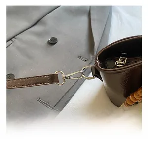 Close-up of silver metal hook and wood bead decoration on a brown leather bucket bag