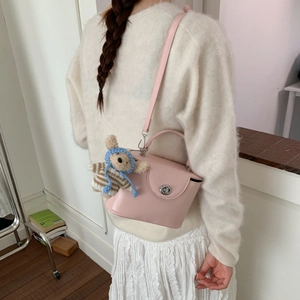 Pink leather crossbody box bag with metal buckle and cute bear charm shown in use