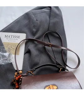 Detail of dark brown retro shoulder bag with rotating metal lock and colorful wood beads