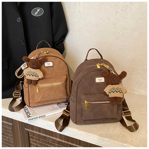 Detail von Vintage-Rucksäcken in Khaki und Kaffee mit niedlichen Bärenanhängern
