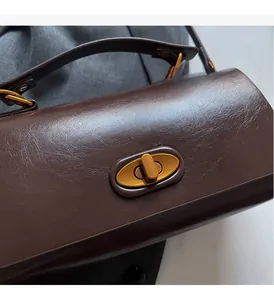 Detail of vintage gold swivel lock and textured dark brown leather on a crossbody bag