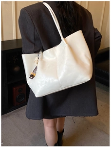 Détail du grand sac cabas blanc porté à l'épaule avec un pendentif tissé minimaliste