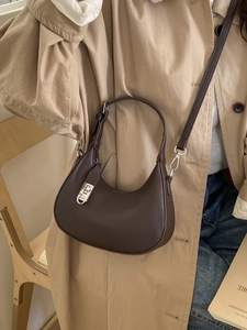 Minimalist dark brown crescent handbag with silver lock shown on a female model