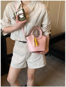 Detailed close-up of pink mini bucket bag with textured leather and wooden bead handle charm