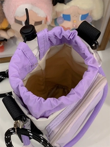 Detail of nylon crossbody bag with purple and white panels and drawstring closure