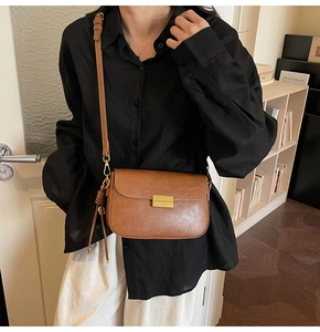 Close-up of vintage brown crossbody bag with gold lock and knotted side details