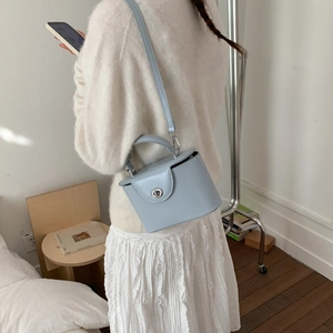 Detail view of a light blue box bag with silver twist lock and slim shoulder strap
