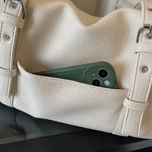 Détail du sac en cuir blanc crème montrant une poche latérale pour smartphone