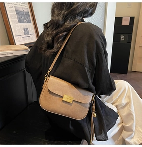 Detail of khaki square crossbody bag featuring golden turn-lock and leather fringe tassel