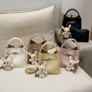 Close-up of pebble leather bucket bag featuring metal twist lock and cute plush charm