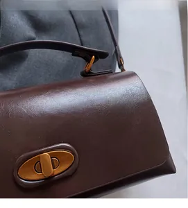 Detail of dark brown leather handbag with vintage golden oval metal twist lock clasp