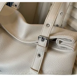 Détail de la bandoulière réglable en cuir grainé avec boucle en métal argenté et œillets