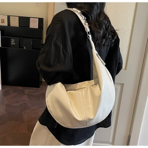 Detail of white glossy hobo bag with quilted stitching and silver buckle on model