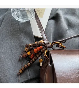 Detail of dark brown leather handbag with vintage wooden bead tassel and metal rings