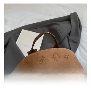 Detailaufnahme des bequemen Tragegriffs und der Katzenprägung auf dem braunen Rucksack