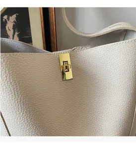 Detailansicht des goldenen Drehverschlusses an einer beigefarbenen Eimertasche