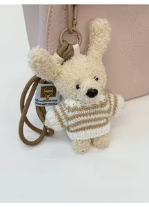 Plush teddy bear charm with crochet striped sweater on a pink leather handbag