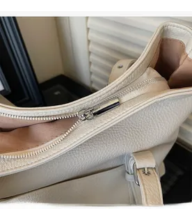 Détail d'une fermeture éclair argentée fluide et cuir à motif litchi sur sac blanc