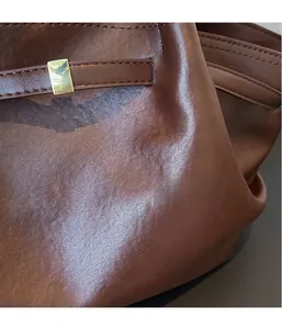 Detail of vintage brown tote bag showing leather texture and gold rectangular buckle