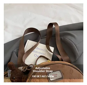 Detail der braunen runden Tasche mit Cartoon-Prägung und verstellbarem Riemen