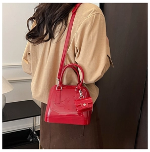 Detail of red jelly PVC shell bag with mini charm and adjustable strap worn as crossbody