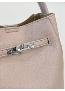 Close-up of pink litchi grain leather and silver metal lock on a bucket tote bag