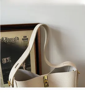 Detail der cremefarbenen Handtasche mit goldenem Drehverschluss und verstellbarem Riemen
