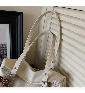 Détail de la poignée du sac cabas en cuir crème avec boucle argentée et charm à pois
