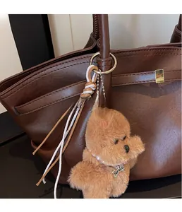 Plush brown dog charm with pearl necklace and bone tag on vintage brown leather tote bag