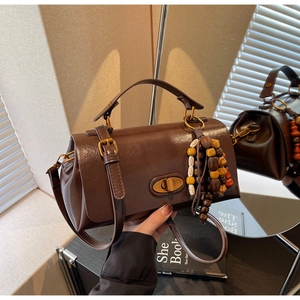 Detail of vintage dark brown crossbody bag with gold twist lock and beaded tassel charm