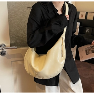 Close-up of beige leather crescent shoulder bag with metallic zipper and wide strap detail