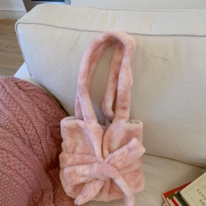 Detail of pink plush tote bag showing soft faux fur texture and large bow decoration
