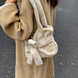 Detail of plush tote bag with leopard pattern and large bow on a camel coat outfit