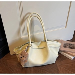 Close-up of cream PU leather tote bag with a cute brown plush bear charm