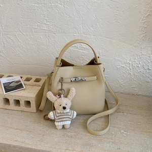 Detail view of cream bucket bag with silver twist lock and cute plush rabbit charm